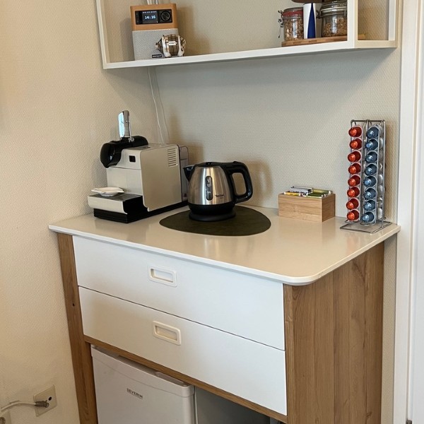 Kitchenette met Nespresso-apparaat, waterkoker, minikoelkast en koffiecups